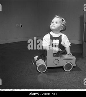 Kinder im 1950er. Jahrhundert. Ein kleiner Junge sitzt ordentlich gekleidet und gut gepflegt mit seinem Spielzeug, einem Brio Truck. Das Unternehmen Brio begann bereits Anfang des 20. Jahrhunderts mit der Herstellung von Holzspielzeug. Schweden 1951. Kristoffersson Ref. BB41-6 Stockfoto