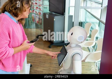 Eine Frau kommuniziert mit einem Roboterberater. Stockfoto
