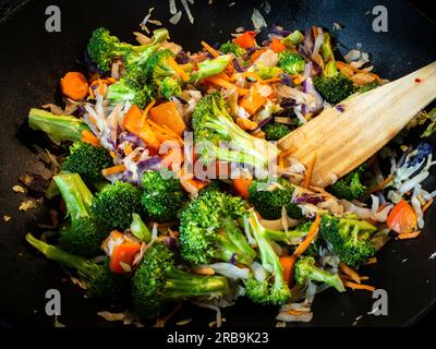 In einer gusseisernen Wok-Pfanne verwöhnt ein köstliches und nahrhaftes vegetarisches Pfannengericht die Sinne. Voller lebhafter Brokkoli, Karotten und ca. Stockfoto