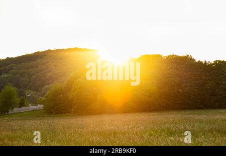 Die Sonnenstrahlen des Sonnenuntergangs über den tiefbewaldeten Bergen. Stockfoto