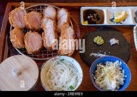 Sous Vide Tonkatsu, gebratenes Schweinefleisch mit Beilagen werden auf dem Teller im Restaurant serviert Stockfoto