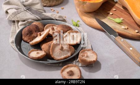 Herbstgemüse auf einer Küchenarbeitsfläche angeordnet, während eine Kürbissuppe zubereitet wird. Stockfoto