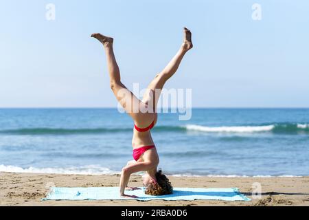 Ruhige Frau im Handstand an der Küste Stockfoto