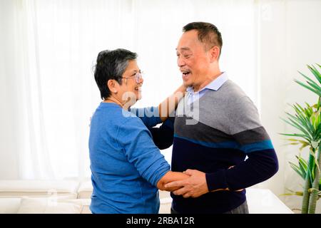 Glücklicher Seniorenmann und Frau, die zu Hause tanzen, glückliches älteres Ehepaar, das Zeit zu Hause verbringt, Großeltern, die sich zu Hause entspannen, glückliche Familie Stockfoto