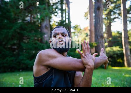 Ein konzentrierter Sportler führt eine Armdehnung durch, um seine Flexibilität zu erhöhen Stockfoto