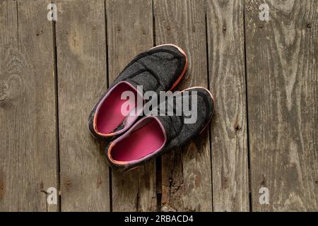 Dreckige Turnschuhe alter Frauen stehen auf dem Holzboden des Hauses Stockfoto
