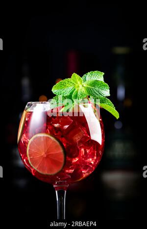 Alkoholische Cocktailgetränke aus königlicher Limonade mit Tequila, trockenem Gin, weißem Rum, Wodka, Likör, Limette, Himbeeren und Eis in Weinglas. Schwarzer Bartresen Ba Stockfoto
