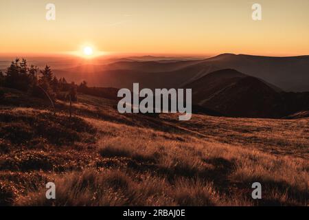 Wunderschöne Natur Sonnenuntergang über dem Horizont auf den Gipfeln des Berges Krkonose, Sonnenaufgang, Europa, Tschechische Republik, Berge, Hügel, weite Landlandschaft Stockfoto