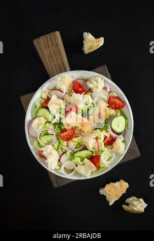 Salat Fettoush mit Pita-Brot, frisches Gemüse auf dem weißen Teller auf dem Holzständer. Traditionelle Gerichte aus dem Nahen Osten oder arabische Gerichte. Vegetarischer Snack. Stockfoto