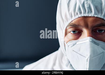 Erschöpfter Arzt in PSA Anzug Uniform in Stress auf schwarzem Hintergrund. Depression, müde Konzept. Nahaufnahme im Hochformat Stockfoto