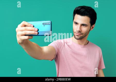 Portrait von stattlichen Mann, der Selfie auf blauem Hintergrund Stockfoto