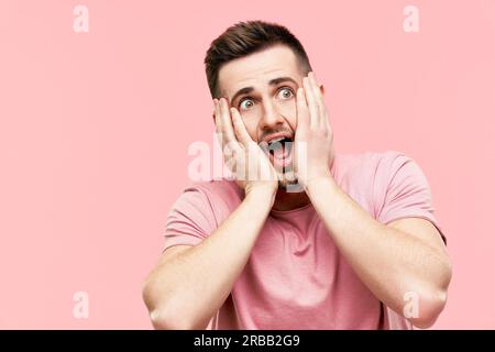 Nahaufnahme eines schockierten, verängstigten Mannes mit offenem Mund, der vor pinkfarbenem Hintergrund Panik hatte. Gesichtsausdruck, omg, Emotionen Konzept Stockfoto