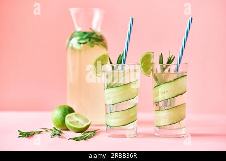 Kalte erfrischende Cocktails mit Limette, Gurke, Rosmarin und Eis im Glas auf rosafarbenem Hintergrund. Party, Sommerkonzept Stockfoto