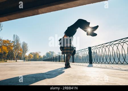 Junger Mann bricht Tänzer tanzen auf städtischen Hintergrund akrobatische Stunts Durchführung. Straßenkünstler beim Breakdance im Freien Stockfoto