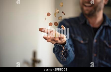 Ein fröhlicher Mann wirft Münzen in die Luft Stockfoto