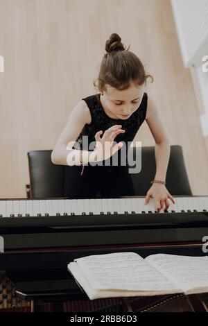 Ein elegantes Mädchen sitzt auf dem Konzert und spielt Klavier Stockfoto