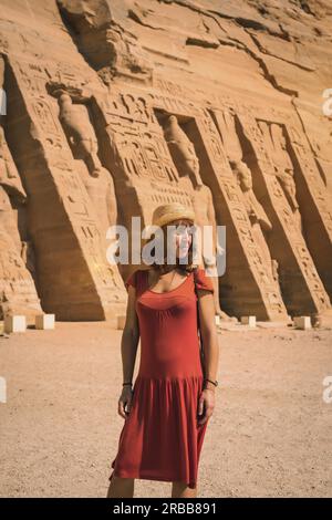 Ein junges Mädchen in rotem Kleid, das den ägyptischen Tempel von Nefertari in der Nähe von Abu Simbel in Südägypten in Nubien neben dem Nasser-See besucht. Tempel des Pharao Stockfoto