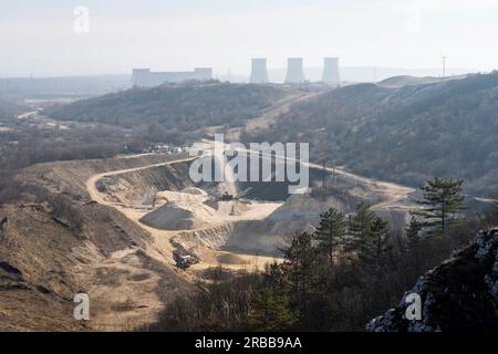 Steinbergwerk mit Maschinen im Hintergrund, altes Wärmekraftwerk und Windturbine Stockfoto