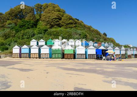 Bournemouth, Großbritannien - Mai 26. 2023: Beach Huts at Middle Chine Beach vor Bäumen auf einer Klippe. Stockfoto