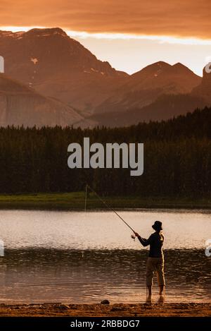 Angeln bei Sonnenuntergang – eine junge Frau, die am Margaret Lake in der Region Waiparous, Alberta, Kanada, angeln möchte Stockfoto