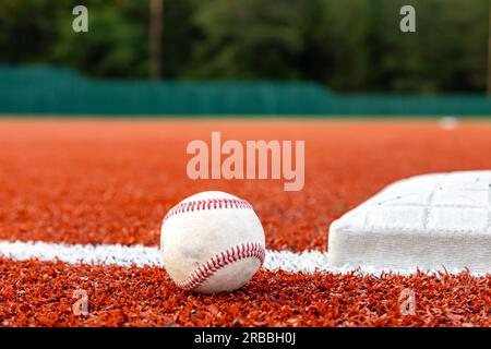 Baseball auf dem Feld neben der Basis für sportlichen Hintergrund mit Kopierbereich Stockfoto