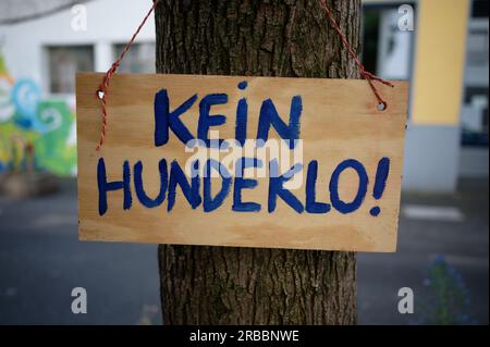 Ein handgemaltes Holzschild mit deutscher Inschrift - keine Hundetoilette - hängt in einer Stadt an einem Baum Stockfoto