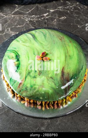Gourmet Pistachio und Strawberry Entremet Cake mit mehrlagigem Schwammkuchen, Pistaziengelee, Erdbeergelee und Erdbeermousse, im Spiegel bedeckt Stockfoto
