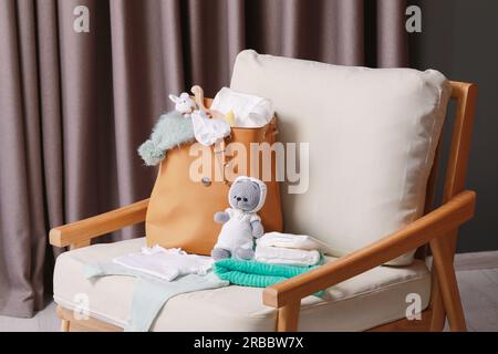 Mutters Tasche mit Babysachen auf einem Sessel im Haus Stockfoto