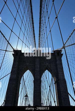 Kabel führen zu einem Turm auf der Brooklyn Bridge vor einem blauen Himmel Stockfoto