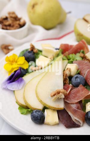 Leckerer Salat mit Brie-Käse, Prosciutto, Walnüssen und Birne auf weißem Teller, Nahaufnahme Stockfoto