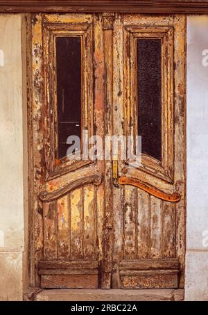 Altes Holzmaterial verblasste und beschädigte Grunge-Eingangstür Stockfoto