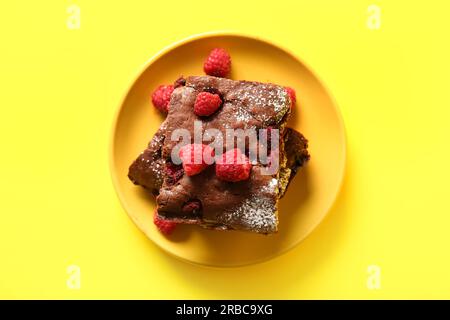Teller mit Himbeer-Schokoladen-Brownie auf gelbem Hintergrund Stockfoto