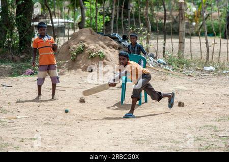 Ein junger Cricketspieler schwingt bei einer Lieferung während eines Spiels in einem Dorf nahe Pottuvil an der Ostküste Sri Lankas. Stockfoto