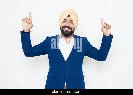 Ein fröhlicher indischer sikh-Geschäftsmann, der Anzug tanzt und Freude hat, isoliert vor weißem Hintergrund. Unternehmenskonzept. Stockfoto