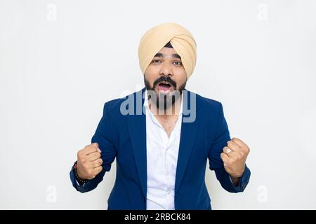 Aufgeregter junger indischer sikh-Mann in blauem Anzug und Turban-Schreien isoliert auf weißem Hintergrund. Stockfoto