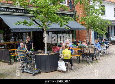 Leute, die auf der Straße vor dem Black Dog Deli Cafe sitzen, Halesworth, Suffolk, England, Großbritannien Stockfoto