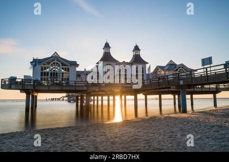 Die Seebrücke Sellin auf der Insel Rügen, einem malerischen Pier an der ruhigen Ostsee, ist von einem glorreichen Sonnenaufgang in goldenem Farbton umgeben. Stockfoto