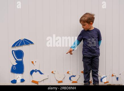 Hilkenbrook, Deutschland-06.05.22: Kind, das mit dekorativen Enten an der Wand posiert. Stockfoto