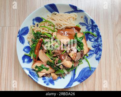 Rinderbraten mit grünem Gemüse und Bohnenquak auf den Nudeln auf dem blauen Gericht Stockfoto