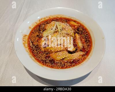 Frisches, würziges und kühles Hähnchen mit Sesam im roten Öl in der weißen Schüssel Stockfoto