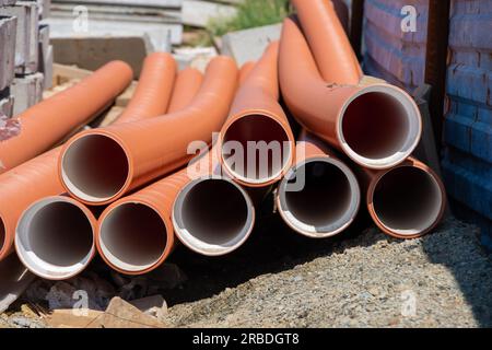 Nahaufnahme roter Rohrleitungen. Drainage, Schläuche, Rohre. Rote Leitungen der Wasserversorgung und der Heizungsanlage. Installation einer Wasserversorgung in einem Land Stockfoto