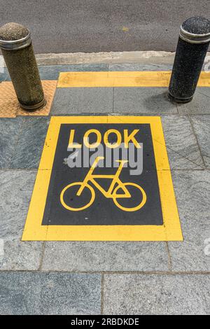 Ein Warnschild, das darauf hinweist, dass Sie beim Betreten der Straße in Singapur auf Radfahrer achten müssen Stockfoto