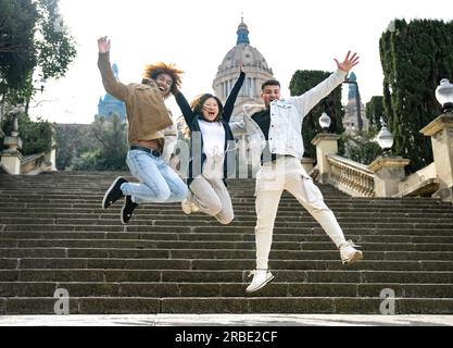 Drei verschiedene junge Leute, die auf eine Treppe springen. Multirassische Gruppe erfolgreicher Menschen, die im Park zusammenspringen. Stockfoto