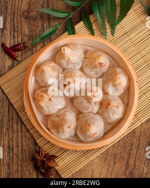 JAKOBSMUSCHELN SUI MAI mit Schweinefleisch und Garnelen，yumcha, Dim Sum, in Hongkong gedünstetes siew Mai Fleischklößchen mit Wantonhaut und Rogen in Bambuskorb asiatisches Dimmfleisch Stockfoto