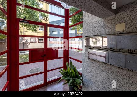Portal eines städtischen Wohngebäudes mit Glas- und roten Metalltüren und polierten Granitfliesenwänden Stockfoto