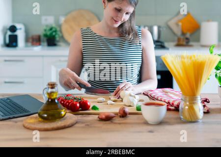 Eine wunderschöne Frau, die kocht und Spaß in der Küche hat. Mädchen kocht gesunde Mahlzeit in der Küche. Stockfoto