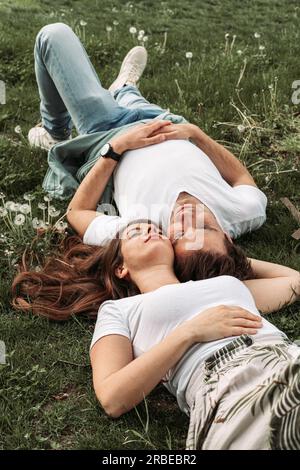 Ein junges romantisches Paar, das im Gras liegt, sich amüsiert, sich erholt Stockfoto