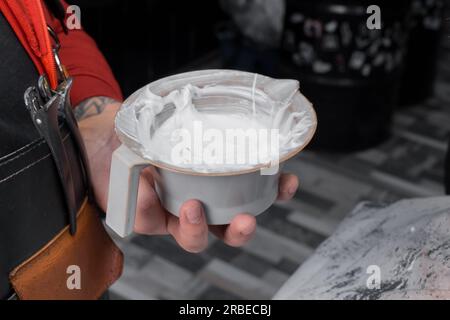 Weiße Farbfärbung in einem Behälter zum Färben der Haare des Kunden bei der Arbeit. Stockfoto