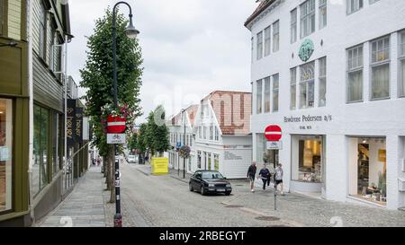 Blick auf eine ruhige, leere Straße mit traditionellen weißen Holzhäusern und moderneren Gebäuden und malerischen Geschäften entlang einer schmalen Straße Stockfoto