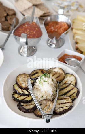 Leckeres mediterranes Frühstücksbuffet mit gegrillten Auberginen-Scheiben, gebürstet mit köstlichem Olivenöl auf einem Teller um einen großen Haufen Sauerkraut Stockfoto